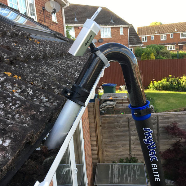 SkyVac suction pole with SkyCam attachment positioned at the gutter of a tiled roof