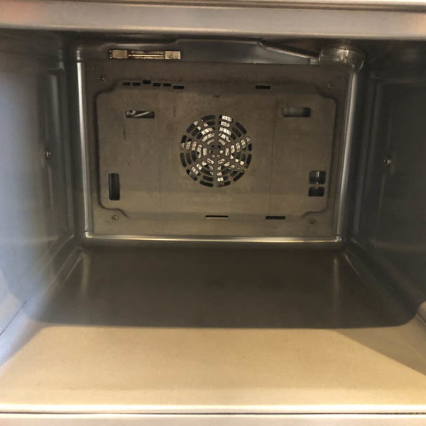 Clean oven interior with pale enamel base, clear side walls and a clean fan cover