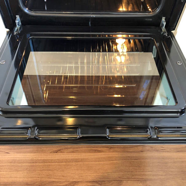 Open oven door with spotless glass and a polished black enamel frame