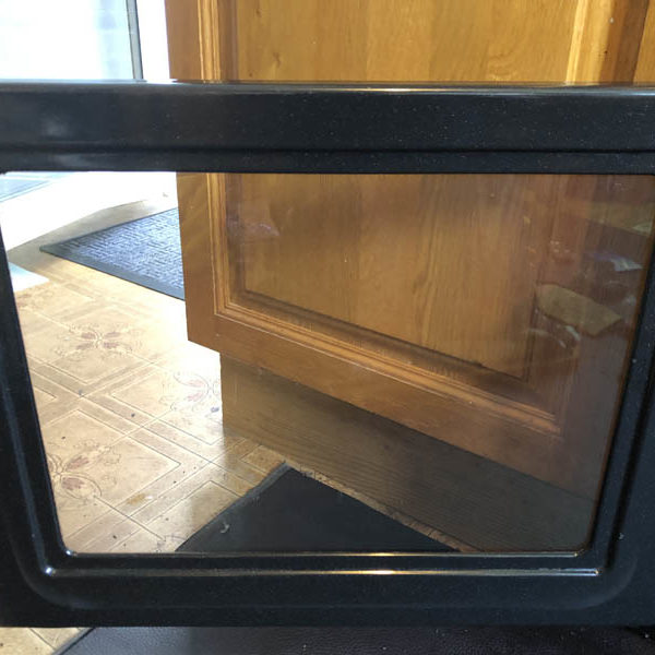 Cleaned oven door with clear glass reflecting the kitchen floor and cupboards