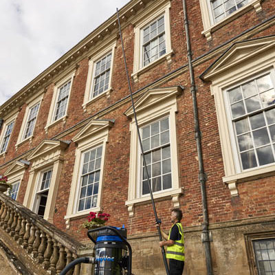 Operative clearing gutters on a period stone building with a SkyVac suction pole
