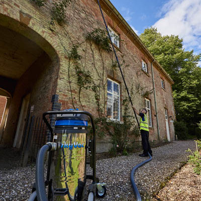 SkyVac Industrial gutter vacuum in the foreground while gutters are cleared above