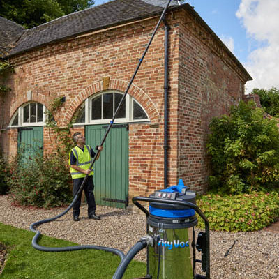 Operative using a SkyVac Industrial suction pole to clear gutters from ground level